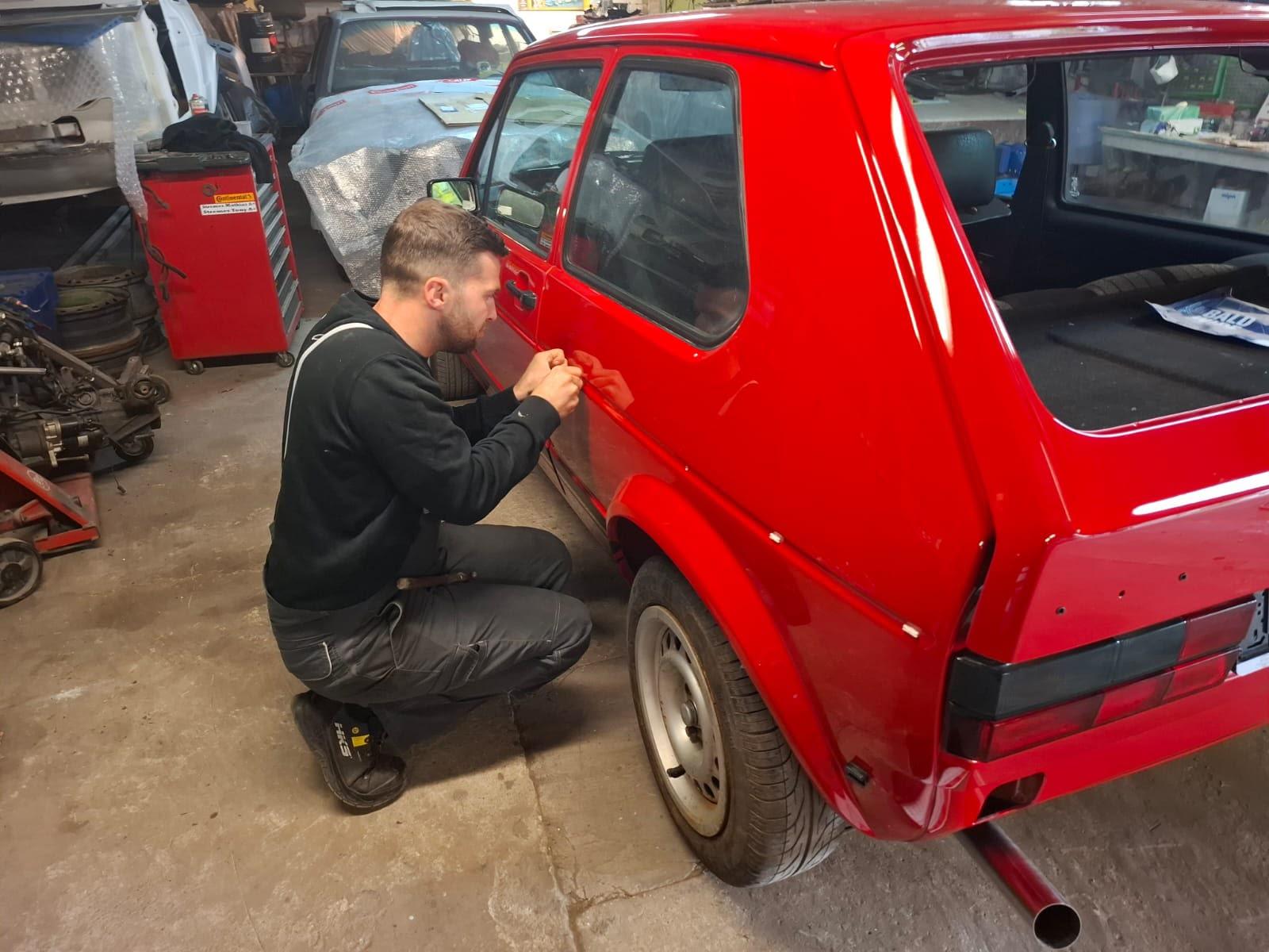 Mathias werkt aan een rode Golf oldtimer in de werkplaats